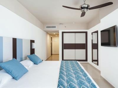 Modernes Hotelzimmer mit Doppelbett, blauen Akzenten und Flachbildfernseher an der Wand.