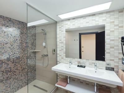 Helles Badezimmer mit Doppelwaschbecken, großer Spiegel und moderner Duschkabine.