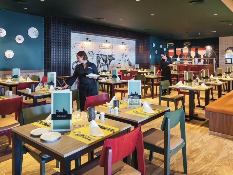 Ristorante dell'hotel moderno con tavoli colorati e cameriera in divisa.