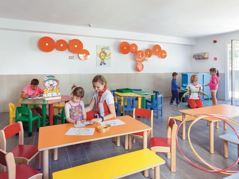 Sala giochi colorata per bambini con tavoli, sedie e giocattoli in hotel.