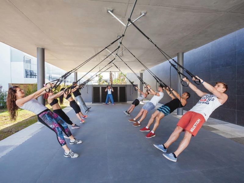 Persone che fanno esercizi di sospensione sotto una struttura in un ambiente moderno.