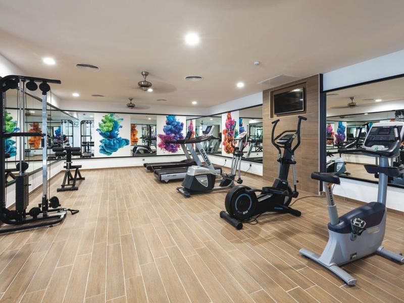 Palestra moderna con attrezzature varie e grandi finestre.