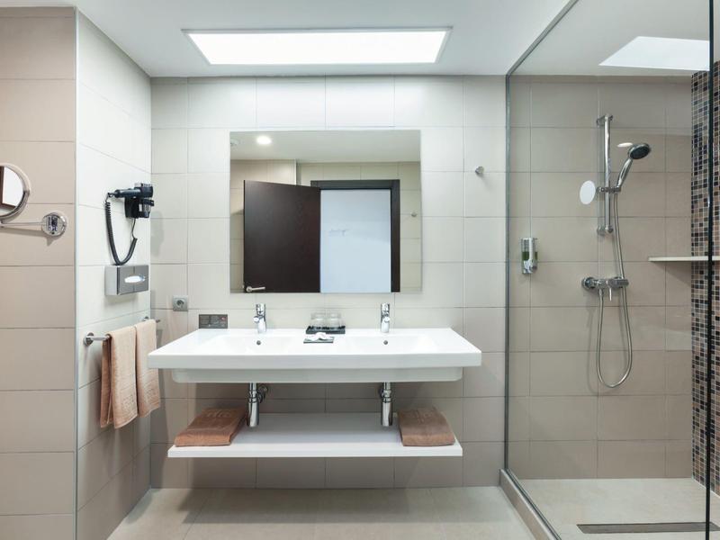 Bagno moderno con doppio lavabo, grande specchio e doccia in vetro.
