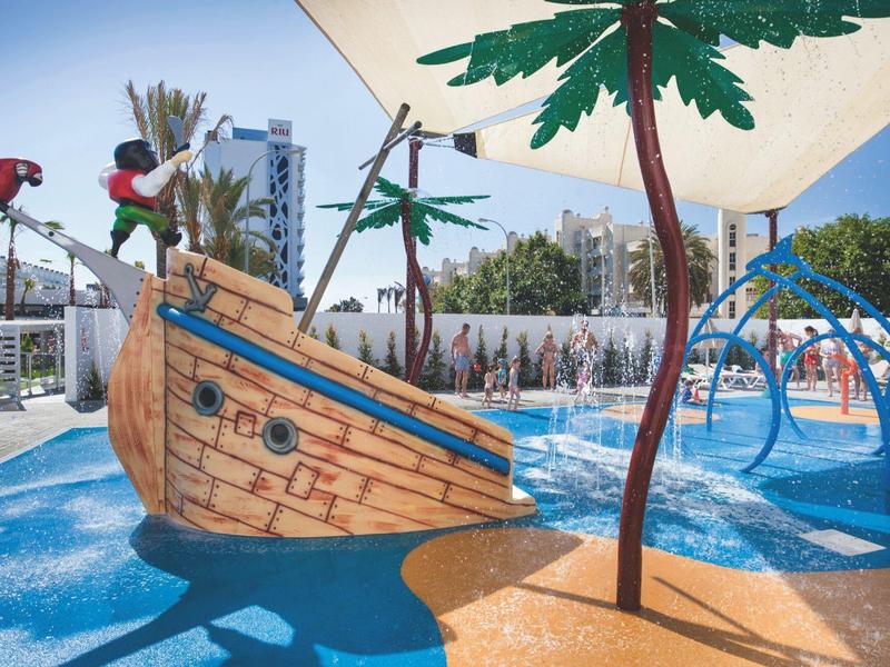 Area giochi acquatica con nave pirata, scivoli e palme artificiali.