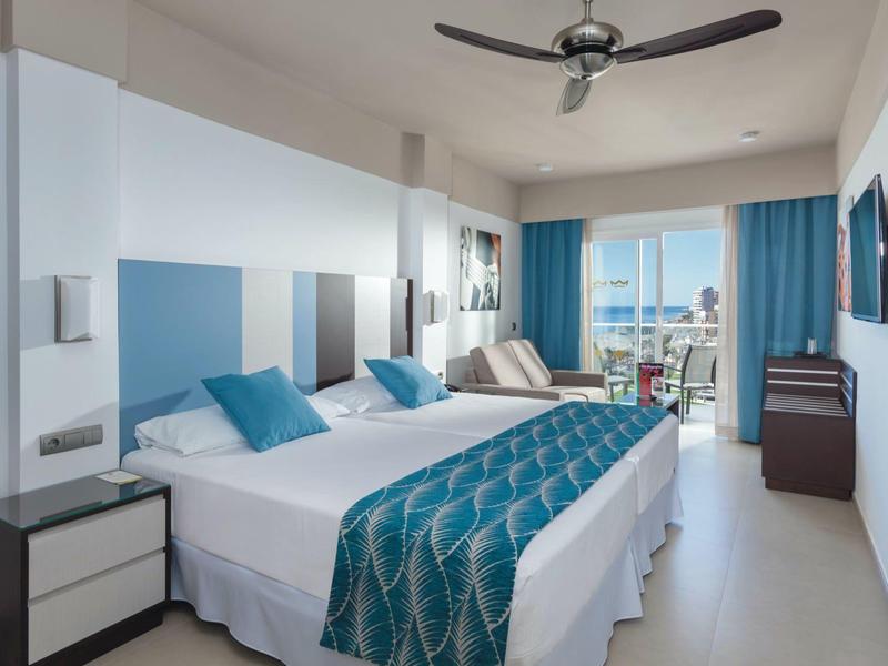 Camera d'hotel moderna con letto matrimoniale, balcone e vista sul mare.