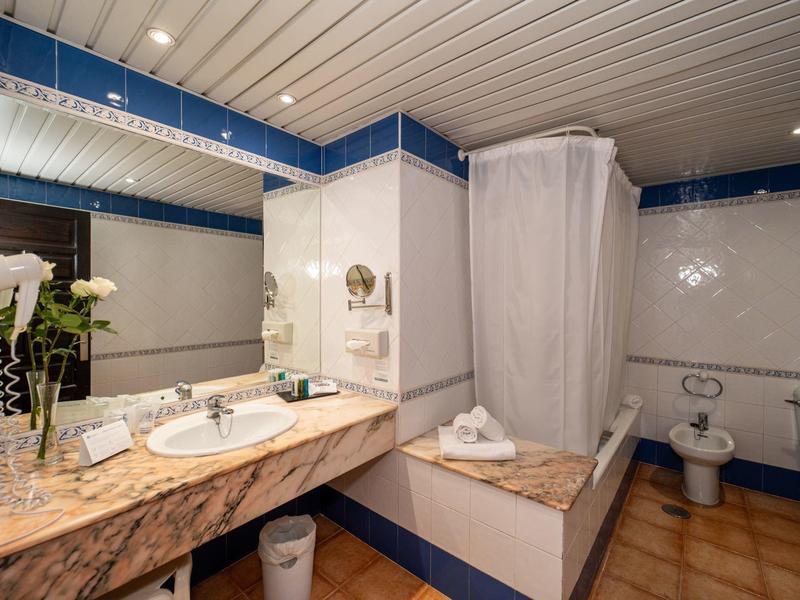 Salle de bain luxueuse avec lavabo en marbre et cabine de douche pluie à l'hôtel.