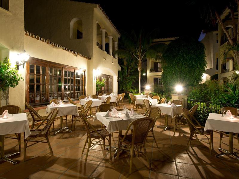 Terrasse d'hôtel la nuit avec tables et chaises dressées sous un éclairage chaleureux.