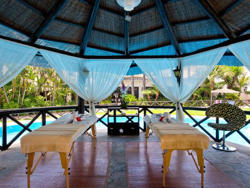 Salles de massage ouvertes avec vue sur une piscine en milieu tropical.