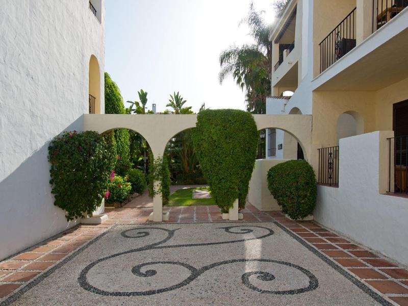 Cour intérieure avec arches décoratives et haies taillées entre les bâtiments