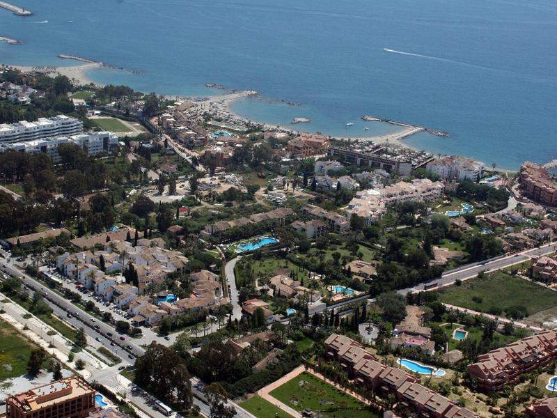 Vue aérienne d'une ville côtière avec plages, hôtels et espaces verts.