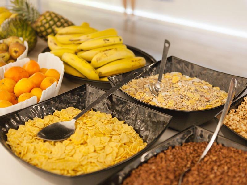 Buffet with various cereals, bananas, and other fruits.