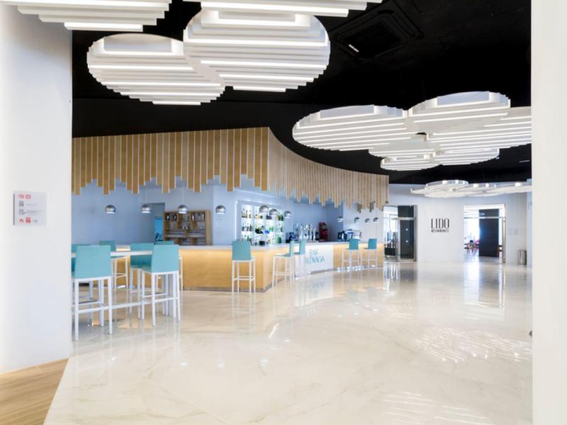 Modern hotel restaurant with large cloud-shaped ceiling lights and bright marble floor.