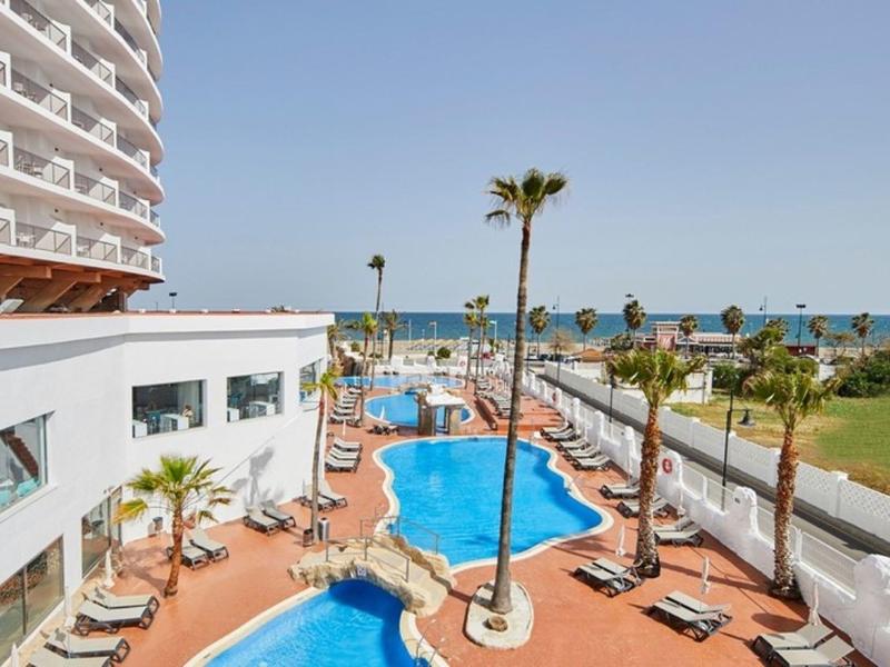 Hotel pool area with lounge chairs and view of the beach and sea