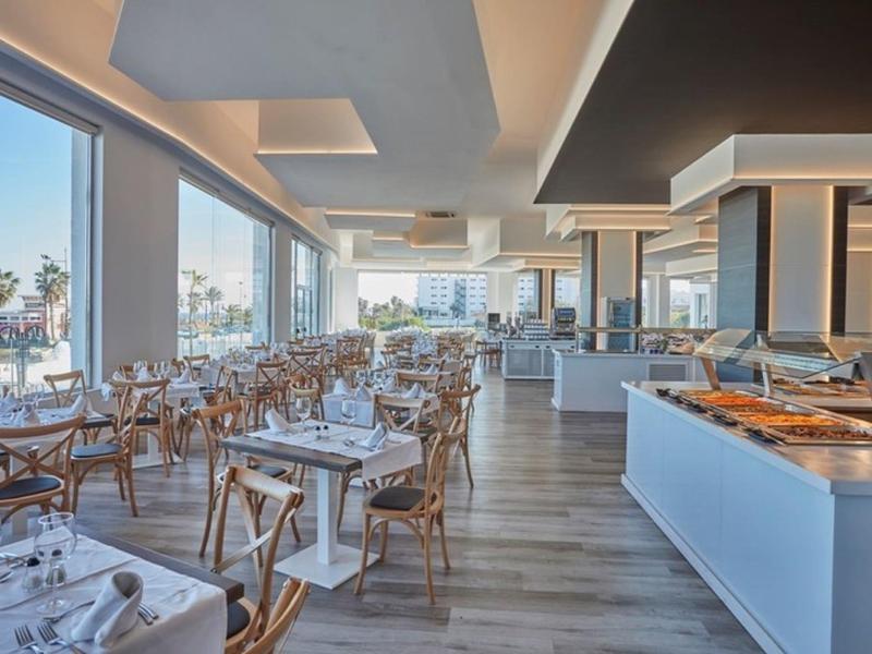 Bright restaurant with large windows, wooden flooring, and buffet station with various dishes.