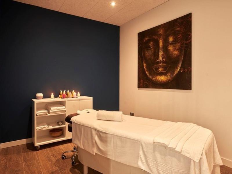 Cozy massage room with table, towels, and relaxing Buddha artwork.