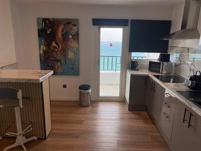 Cucina moderna dell'hotel con vista mare attraverso porta a vetri che conduce al balcone.