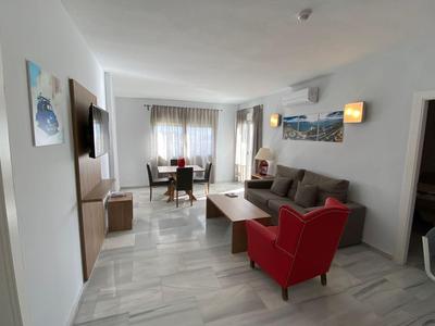 Modern eingerichtetes Wohnzimmer mit rotem Sessel, grauem Sofa und Esstisch in einem hellen Raum.