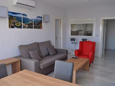 Zona giorno moderna con divano grigio, poltrona rossa e tavoli in legno in una stanza luminosa