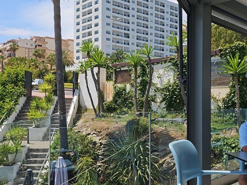 Vista da una terrazza dell'hotel con posti a sedere su un giardino e un edificio dell'hotel a più piani.