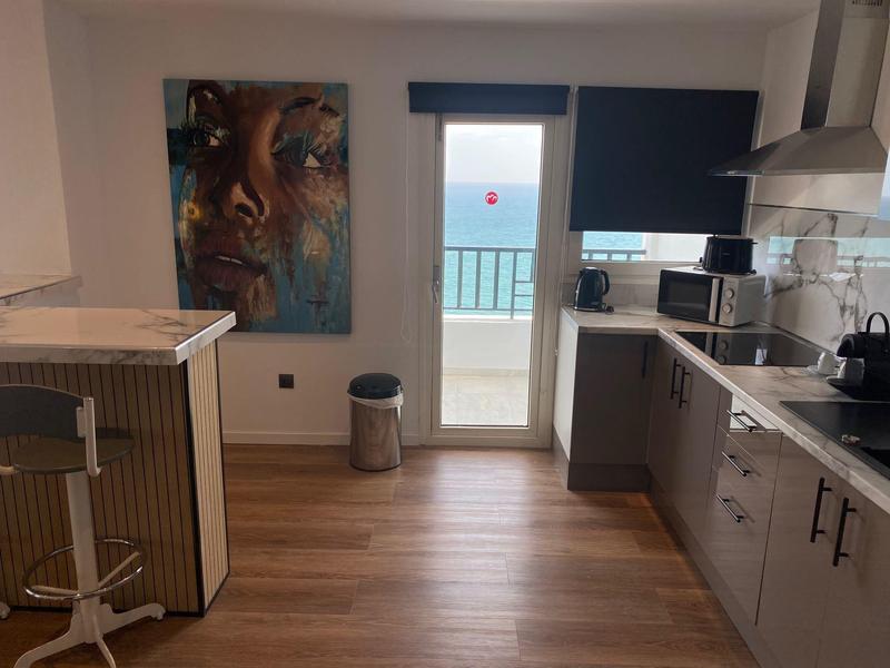 Cucina moderna dell'hotel con vista mare attraverso porta a vetri che conduce al balcone.