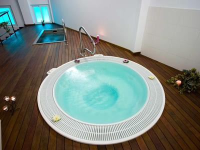 Espace intérieur moderne avec jacuzzi rond sur sol en bois et piscine en arrière-plan