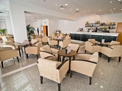 Espace lounge d'hôtel moderne avec fauteuils beiges et petites tables.