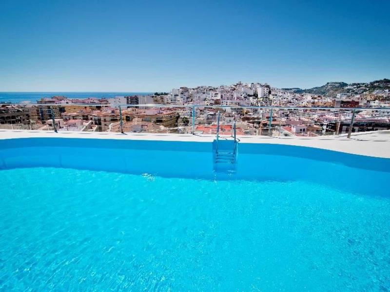 Piscine bleu clair avec vue sur une ville et la mer en arrière-plan