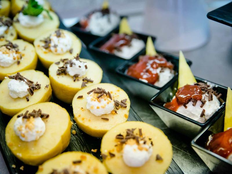 Différents petits desserts sur un plateau, y compris des cupcakes avec de la crème et des morceaux de chocolat.