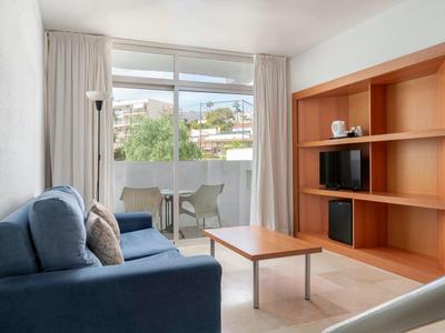 Cozy hotel room with a blue sofa, wooden shelves, balcony, and view outside.
