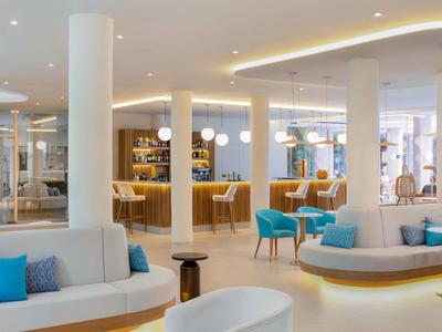 Moderne Hotellounge mit bequemen Sitzgelegenheiten und stilvoller Bar in hellem Ambiente.