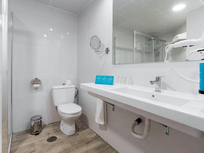 Modernes Hotelbadezimmer mit Toilette, Waschbecken und großen Spiegel.
