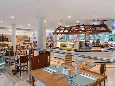 Helles, modernes Hotelrestaurant mit Holzstühlen, Glastischen und Buffetstation