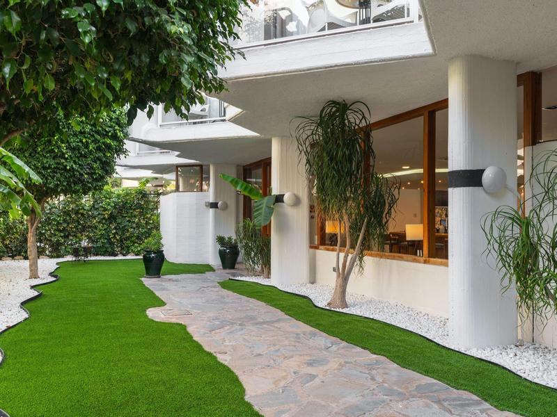 Curved stone pathway alongside a green lawn beside a white building with large windows.