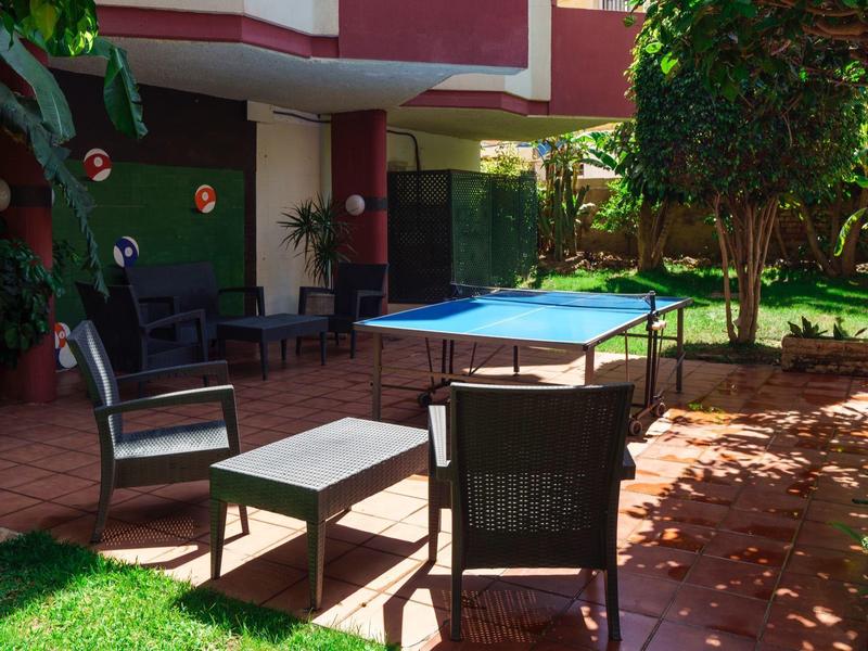 Outdoor patio with chairs and a table near a ping pong table in a garden.