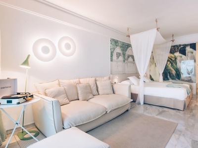 Helles Hotelzimmer mit großem Sofa, Himmelbett und stilvoller Wanddekoration.