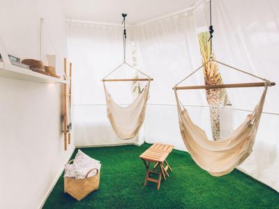 Helle Hotelterrasse mit grünen Teppich, zwei beigen Hängesesseln und kleinem Holztisch.
