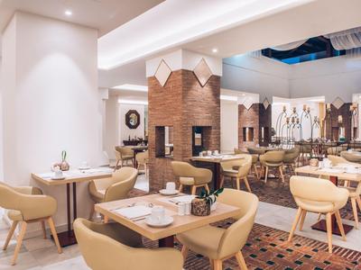 Moderner Frühstücksraum mit bequemen Stühlen, Holztischen und warmem Licht in einem Hotel.