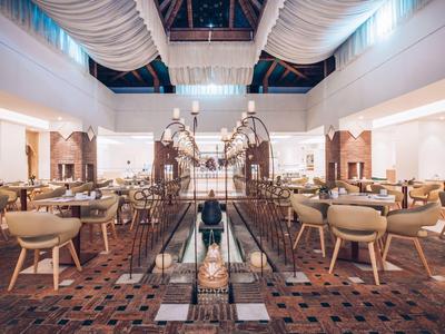 Großer, heller Hotel-Lobbybereich mit eleganten Sesseln und dekorativem, zentralem Lichtobjekt.