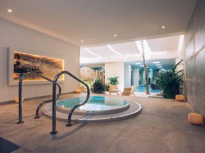 Moderner Innenbereich mit kleinem runden Pool, Pflanzen und warmem Licht für Entspannung.