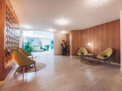 Heller, moderner Hotellobby-Bereich mit Holzpaneelen, Sesseln und Pflanzen.