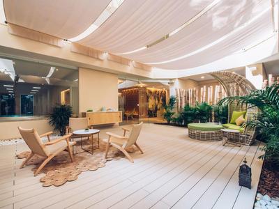 Elegante Hotellobby mit Holzstühlen, Teppich, grünen Pflanzen und sanfter Beleuchtung.