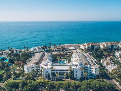 Großes Hotelresort an der Küste mit Pool, umgeben von grünem Wald und Blick auf das Meer.