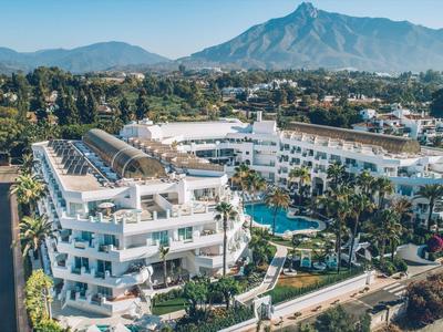 Luxuriöses Hotelresort mit Pool, umgeben von Bergen und Palmen.