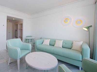 Hell eingerichtetes Wohnzimmer mit mintgrünem Sofa, Sesseln und rundem weißen Tisch.