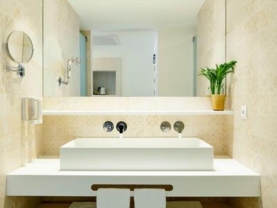 Modernes Badezimmer mit rechteckigem Waschbecken, großem Spiegel und Pflanze auf der Arbeitsplatte.