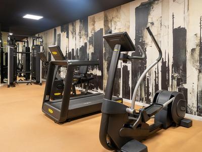 Fitnessraum mit modernen Trainingsgeräten und grafischer Wandgestaltung im Hotel.
