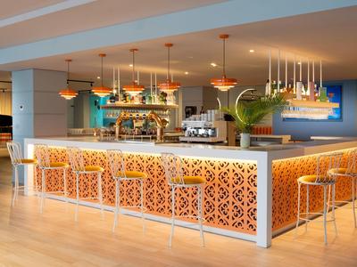 Moderner Hotelbarbereich mit hohen Stühlen und dekorativ beleuchtetem Tresen.