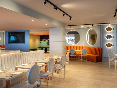 Helles, modernes Restaurant mit stilvollen Sesseln und runden Spiegeln an der Wand.