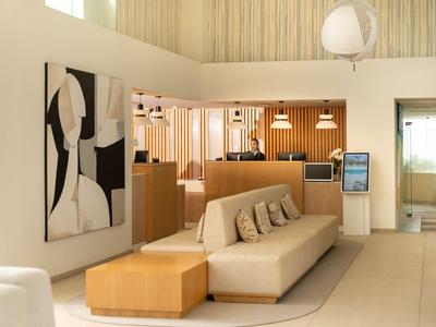 Heller Hotel-Lobbybereich mit beiger Couch, Holzmöbeln und abstrakter Wandkunst.