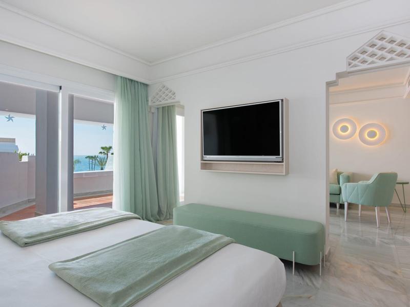 Modern hotel room with double bed, terrace, and sea view.